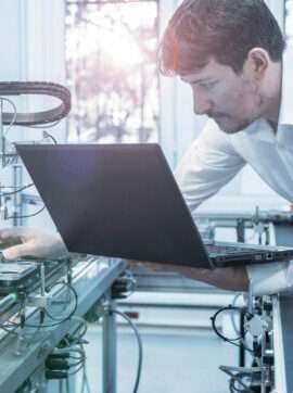 Engineer is working on laptop to program smart factory prototype